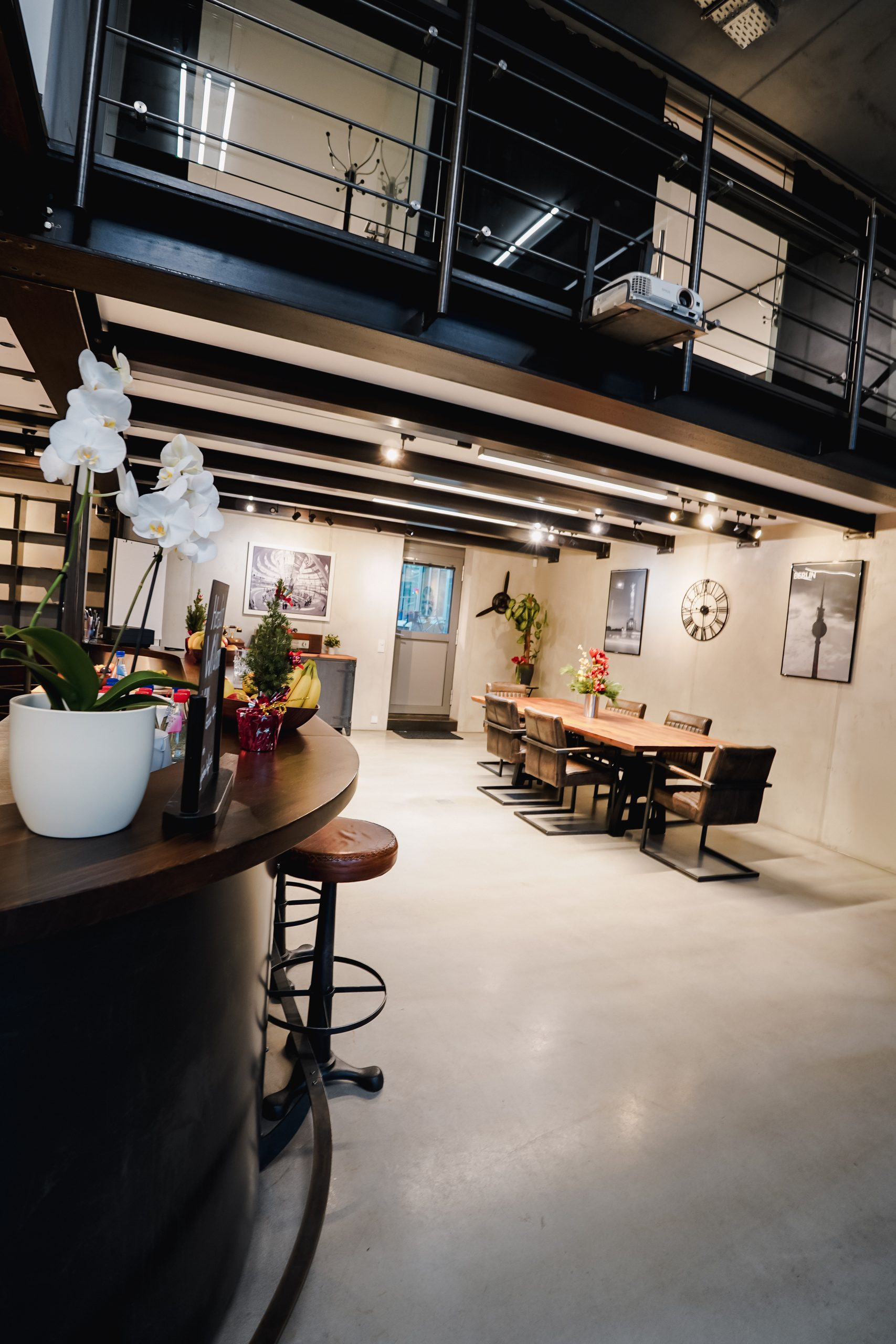 Bar mit Orchideen und Barhockern, Galerie und Arbeitsbereich mit Holztischen im P7 Global Office