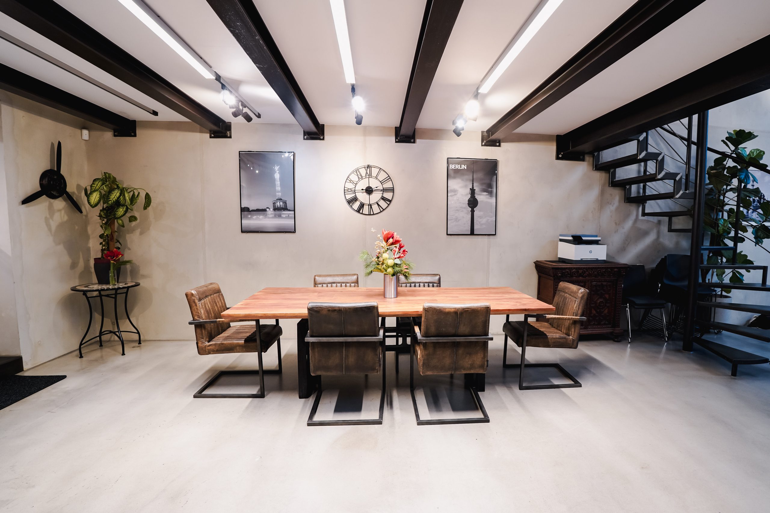 Meeting area with long wooden table, leather chairs, wall clock and Berlin pictures