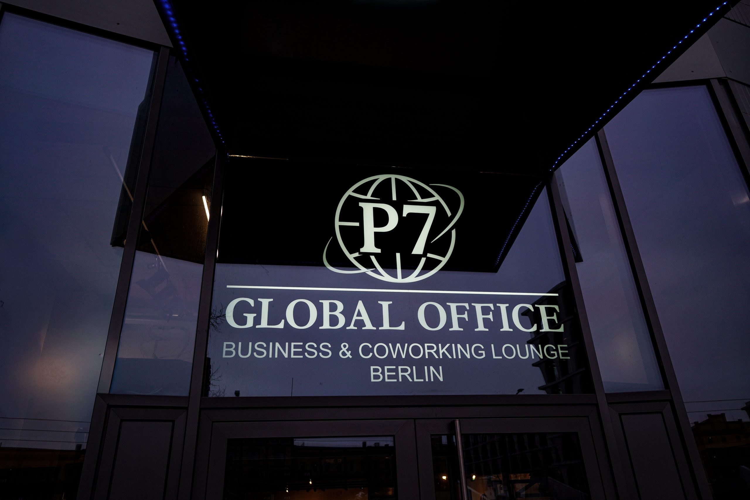Beleuchtetes Logo P7 Global Office Business & Coworking Lounge Berlin über dem Eingang