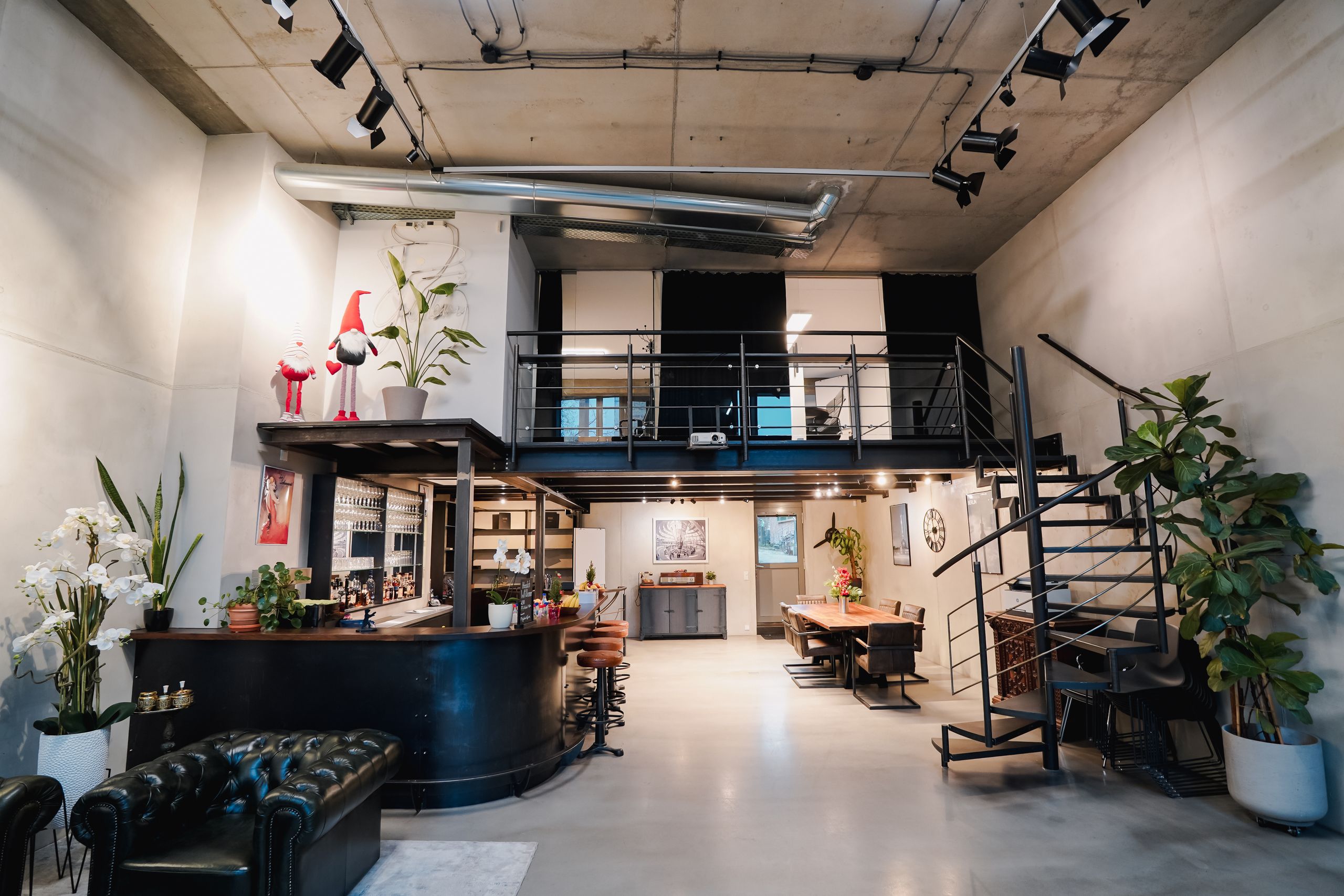 Empfangsbereich mit Tresen, Chesterfield-Sofa, Galerie und Wendeltreppe